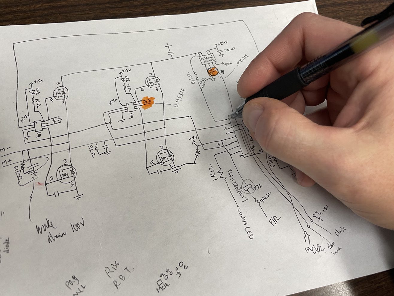 Hand with pen drawing schematic of electronic operation