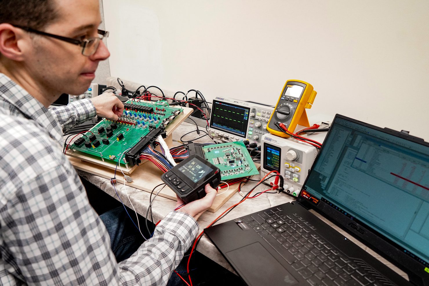 Engineer reviewing values of testing Engineer in front of computer testing components